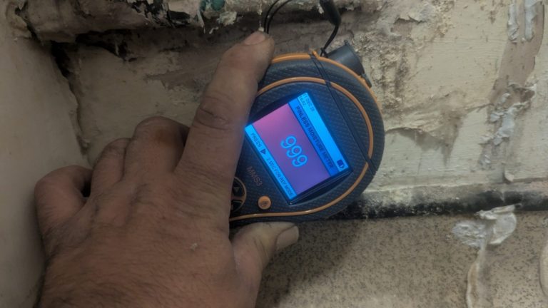 Elevated moisture readings on a wall detected with a moisture meter